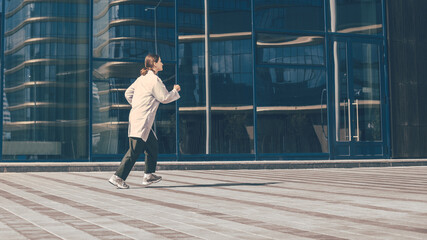 Obraz na płótnie Canvas concerned woman doctor running near a city building.