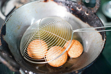 shot of north indian street food snack gol gappe pani puri or puchke being fried from dough in hot oil to make them round hollow golden ball spheres © Memories Over Mocha