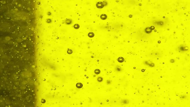 Close up shot with slowmo of air bubbles floating in yellow liquid