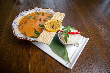 Traditional spicy Thai soup Tom Yum and various ingredients around. Served with rice.