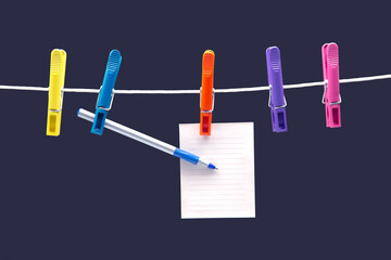paper notepad for reminder and pen hanging on colored clothespins