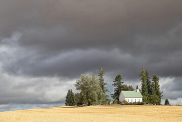 Original landscape photograph of a little white church under ominous dark rain clouds