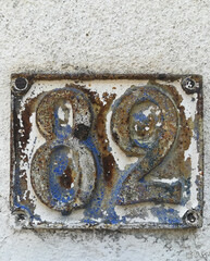 Vintage grunge square metal rusty plate of number of street address with number. Close up, brand.
