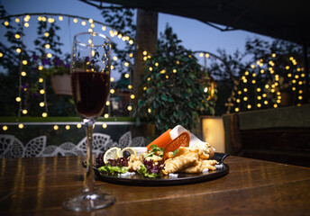 Crispy Fish and Chip with side dish, cheese potatoes and spicy sauce on a black plate