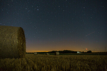 hay bails at night under stars in a field