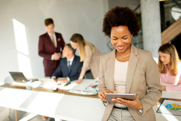 African American businesswoman standing and using digital tablet in a modern office