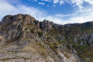 a panoramic view of the beautiful mountains with unusual ledges and rocks against the background of the sky and the valley filmed from a drone