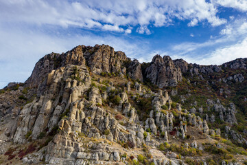 a panoramic view of the beautiful mountains with unusual ledges and rocks against the background of the sky and the valley filmed from a drone
