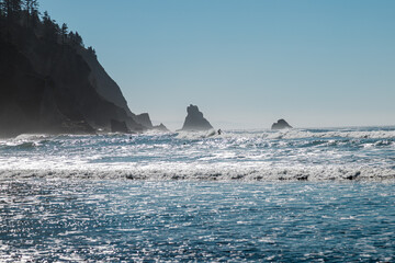Fototapeta na wymiar Silhouette of Surfers Riding Waves With Sharp Cliffs