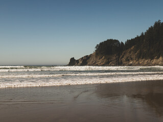 Surfers Silhouette in the Distance with Huge Cliff Meeting the Ocean