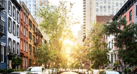 Block of historic buildings on a tree lined street in Midtown Manhattan, New York City with sunlight background