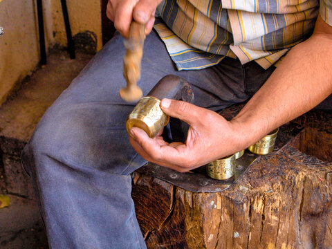Traditional workshop of a master coppersmith making a hand-made artisan  carved brass metal shots