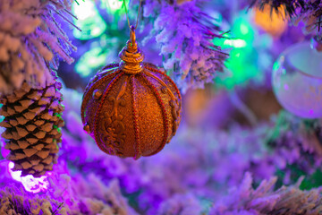 Obraz na płótnie Canvas beautiful Christmas ball on an artificial Christmas tree, to the left of the ball hangs a big bump, on the Christmas tree hangs a colored garland and Christmas decorations