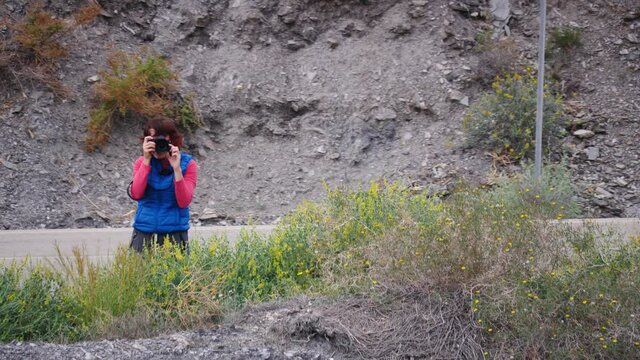 Tourist woman taking travel picture with professional camera on mediterranean nature in wintertime, Spain