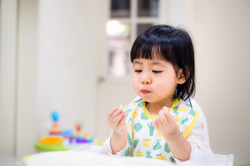 Baby eating bread. Asian baby girl enjoys a meal. baby-led weaning. - 384820735