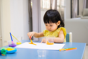 child painting with a paintbrush on the table. toddler draw watercolor. - 384820755