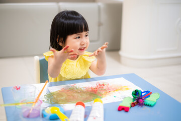 happy Toddler painting water color with her hand. smiley baby girl with painted hand. - 384820916