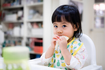 Baby eating bread. Asian baby girl enjoys a meal. baby-led weaning. - 384820968