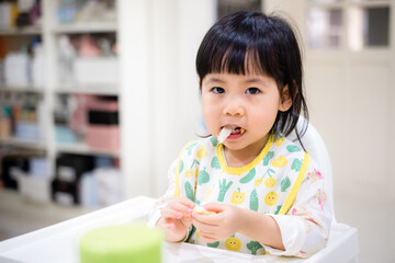 Baby eating bread. Asian baby girl enjoys a meal. baby-led weaning. - 384820987