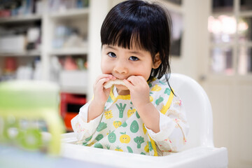 Baby eating bread. Asian baby girl enjoys a meal. baby-led weaning. - 384821120