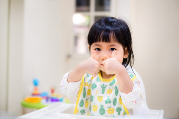 Baby eating bread. Asian baby girl enjoys a meal. baby-led weaning. - 384821136