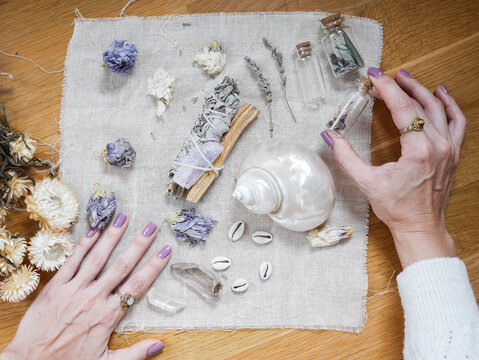 A girl is holding a little glass jar  on her altar in lavender tones