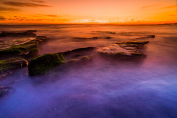 A beautiful sunset with long exposure technique at Mengening Beach Canggu Bali. 
a layer of moss on the beach rock makes a dream beach feel. 
