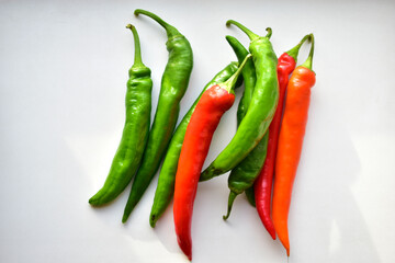 Green and red capsicum fruits on a white background