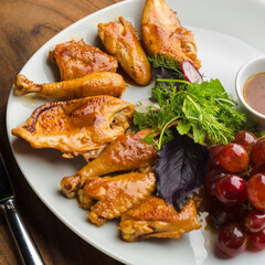 Chicken cooked in wine with grape, served on white plate in restaurant.