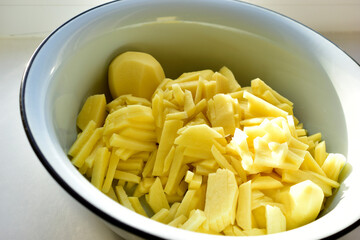 Fresh raw sliced potatoes in an iron basin