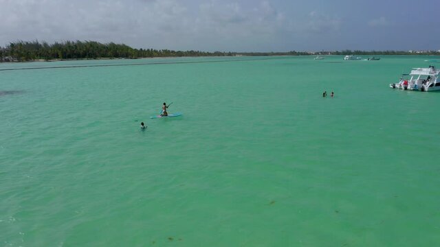 Circling around people swimming and paddle-boarding in incredible turquoise ocean water, Playa Jaunillo, Dominican Republic