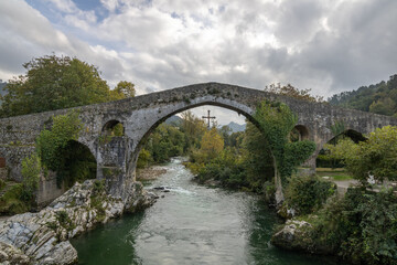 Roman bridge in the city of Cangas de Onis, Spain with the cross of victory hanging from the arch.