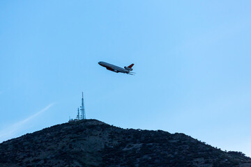 Fototapeta na wymiar Fire tanker plant flies close to communications tower low to the ground circling a wildfire