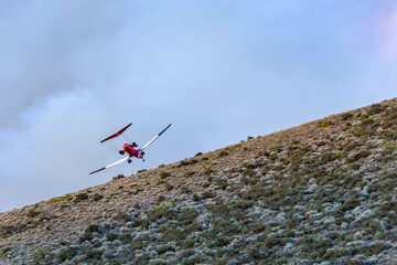 Fototapeta na wymiar Small firefghting plane goes over a hill towards a fire