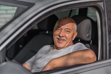 Senior man driving a car, looking at the camera. driving concept. 