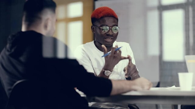 Emotional business conversation between two young businessmen. African colleague talks about the benefits of his business plan. Mutual cooperation concept.
