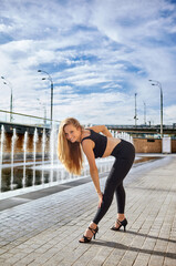 Beautiful woman dancer with long blond hair posing on city street. Female dancing improvisation -...