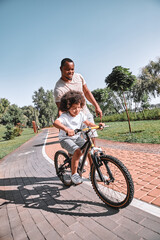 Loving dad assisting his child with riding a bike