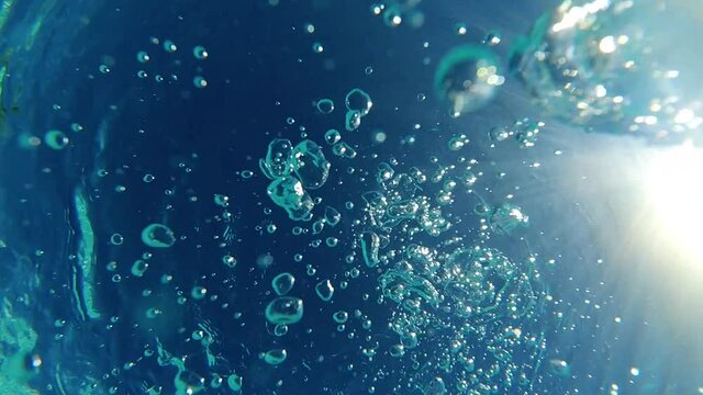 Underwater slow motion bubbles moving to surface in turquoise crystal clear pool