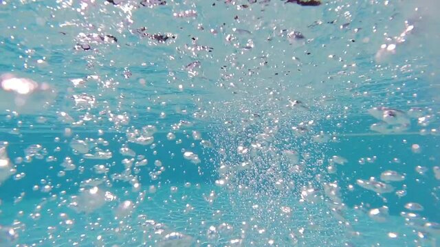 Underwater slow motion bubbles moving to surface in turquoise crystal clear pool
