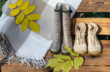 Plaid, boots, rubber boots, yellow autumn leaves on the bench, close-up.