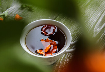 A Cup of tea with marigold flowers on a green wooden background, top view, bokeh - the concept of making medicinal tea from medicinal plants