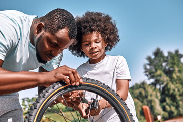 Responsible father fixing a flat tyre of his son bike