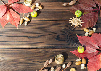 Red autumn leaves, acorns and dry plants on a wooden background.