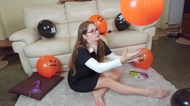 Girl having fun and playing with orange and black Halloween baloons. Children get ready for celebrate Halloween at home, decorate home