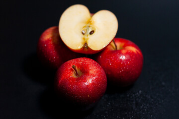 Three whole fresh red apples. On top is one half of a fruit.