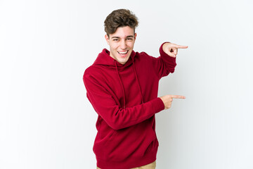 Young caucasian man isolated on white background excited pointing with forefingers away.