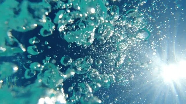 Underwater slow motion bubbles moving to surface in turquoise crystal clear pool