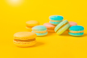 Sweet almond colorful unicorn pink blue yellow green macaron or macaroon dessert cake isolated on trendy yellow modern fashion background. French sweet cookie. Minimal food bakery concept Copy space