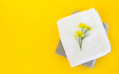 Stack of towels on a yellow background close-up with flowers